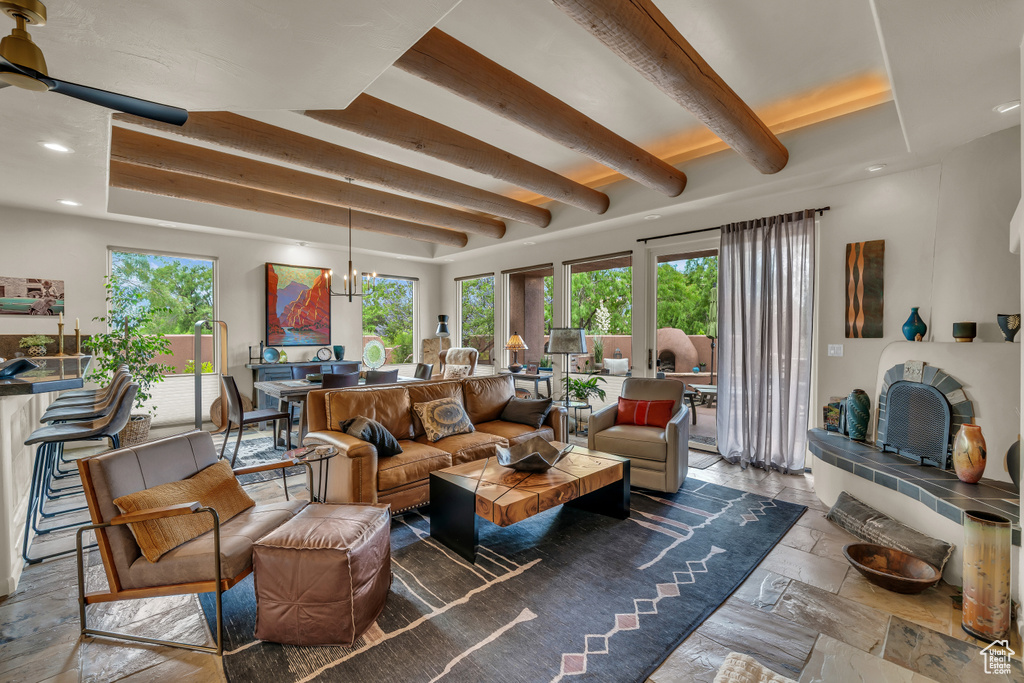 Living room featuring plenty of natural light, beamed ceiling, recessed lighting, stone tile floors, and a chandelier