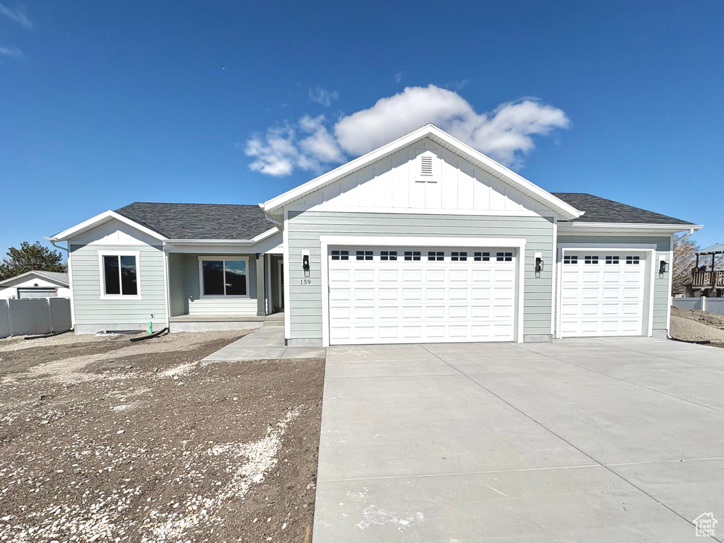 Single story home with an attached garage, concrete driveway, board and batten siding, and a shingled roof