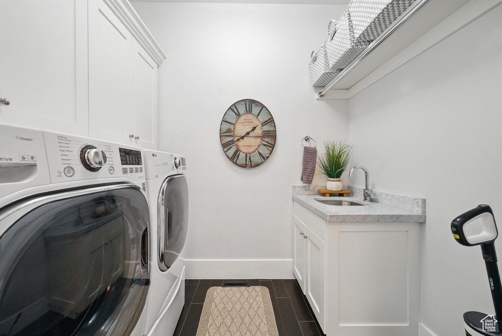 Laundry area featuring separate washer and dryer, cabinet space, and wood finish floors