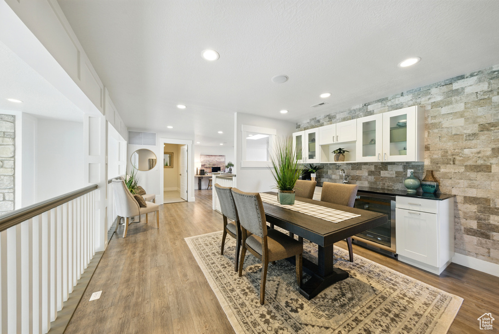 Dining space featuring wine cooler, light wood-style floors, and recessed lighting