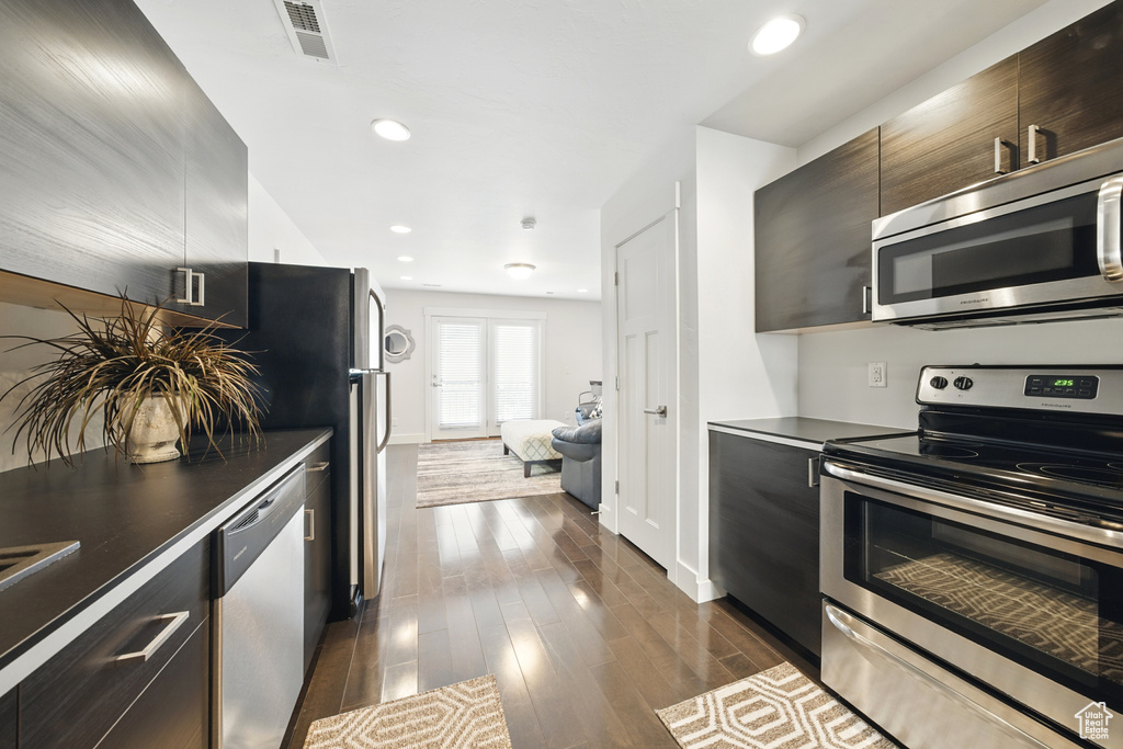 Kitchen with stainless steel appliances, modern cabinets, dark countertops, dark wood-style floors, and recessed lighting