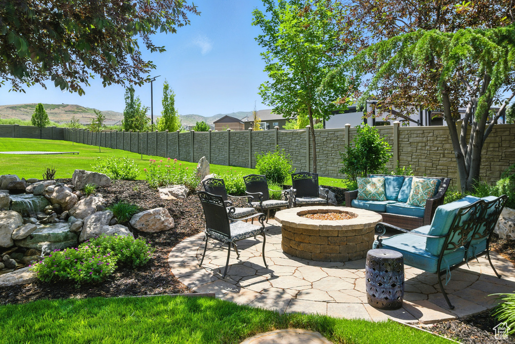 Fenced backyard with a patio, an outdoor living space with a fire pit, and a mountain view