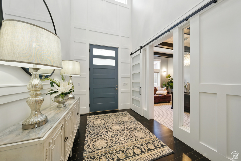 Foyer entrance with a barn door, a decorative wall, a towering ceiling, and wood tiled floors