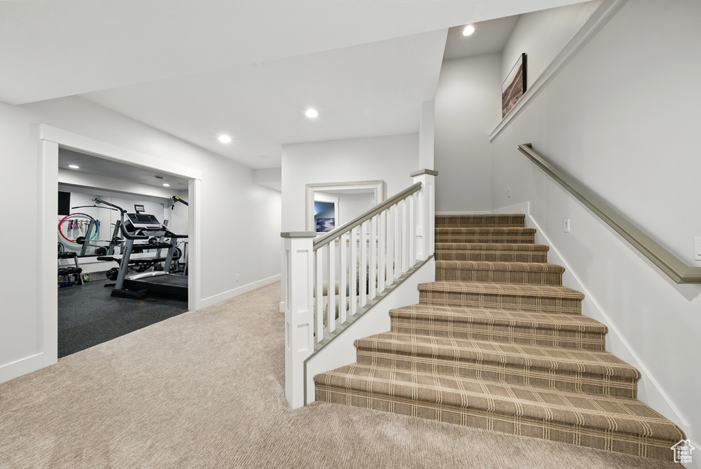 Stairs with carpet floors and recessed lighting