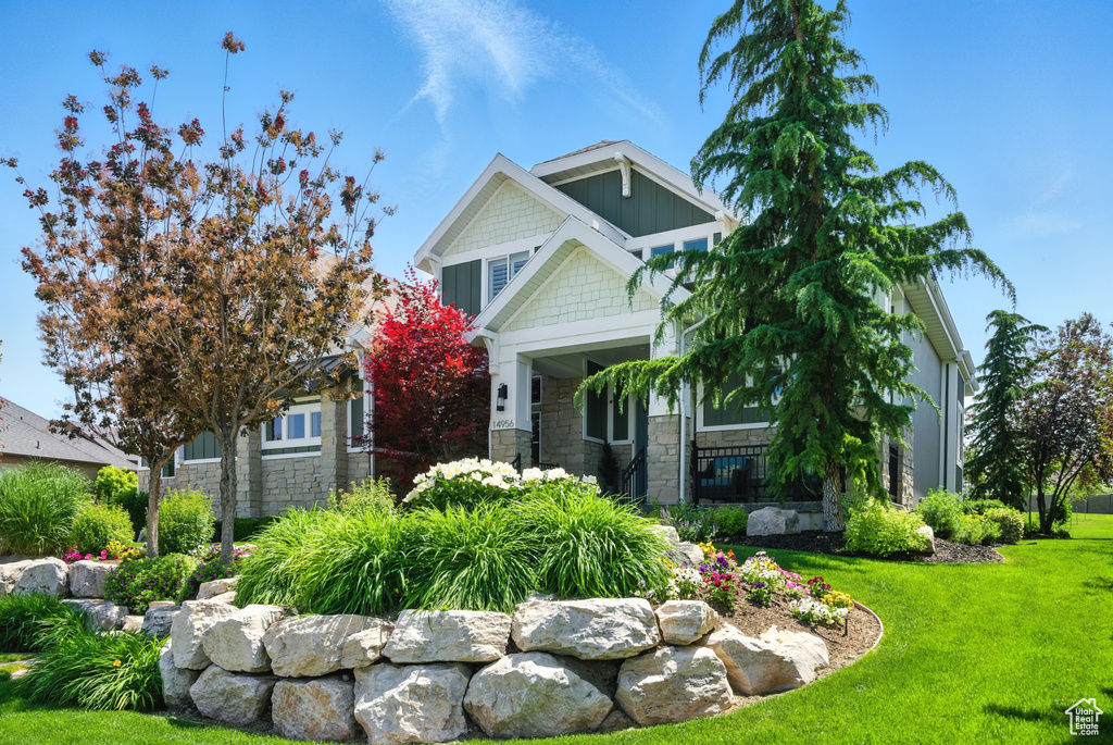 Craftsman-style home with a front yard and stone siding