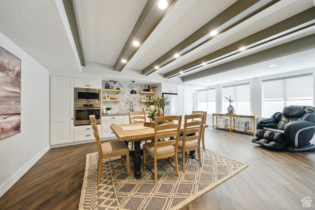 Dining space with dark wood-type flooring, beam ceiling, and recessed lighting
