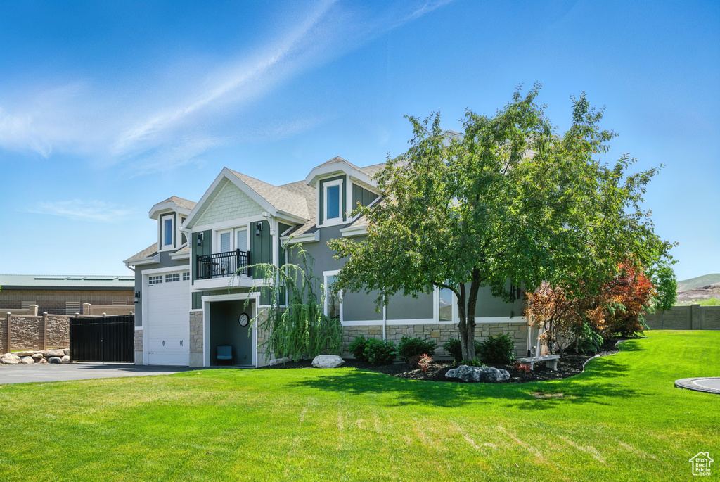 View of front of house featuring a balcony, stone siding, asphalt driveway, and a garage