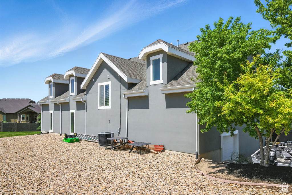 Rear view of property featuring roof with shingles and stucco siding