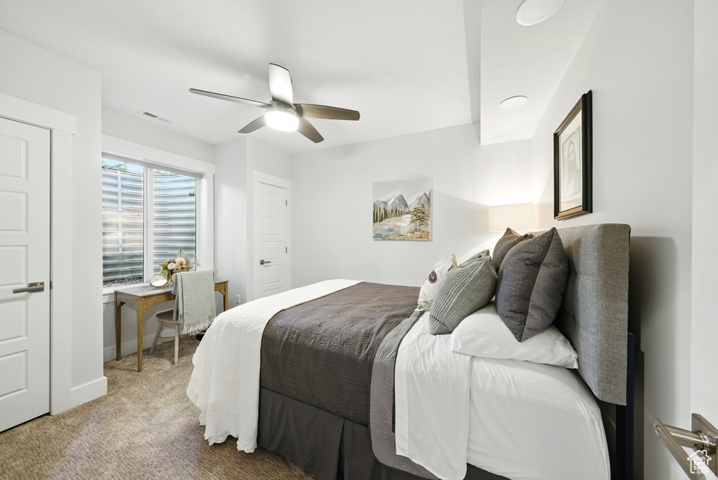 Bedroom with light colored carpet and a ceiling fan