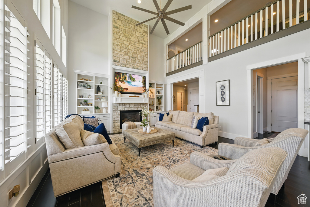 Living area featuring a high ceiling, a ceiling fan, dark wood finished floors, a fireplace, and recessed lighting