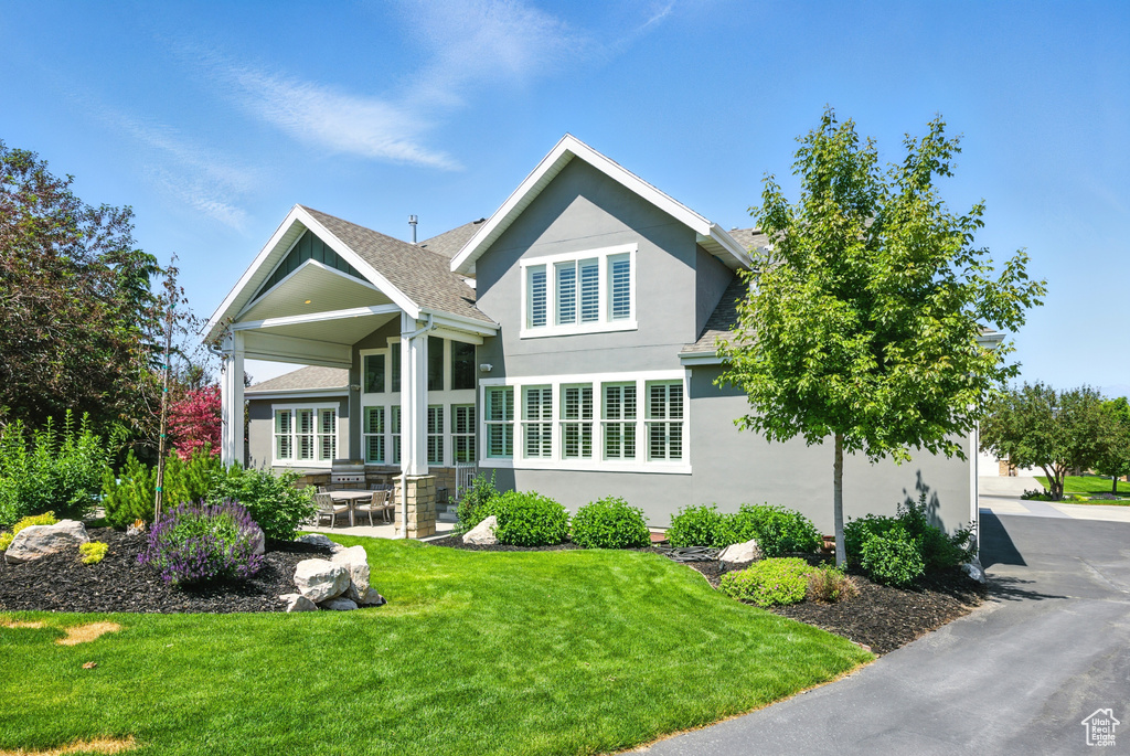 View of front of home featuring stucco siding, a front lawn, a patio area, and roof with shingles