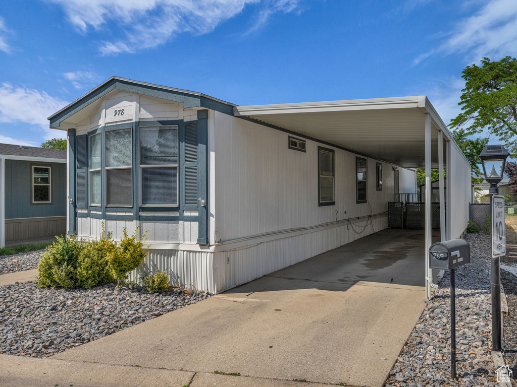 View of front facade with driveway and a carport