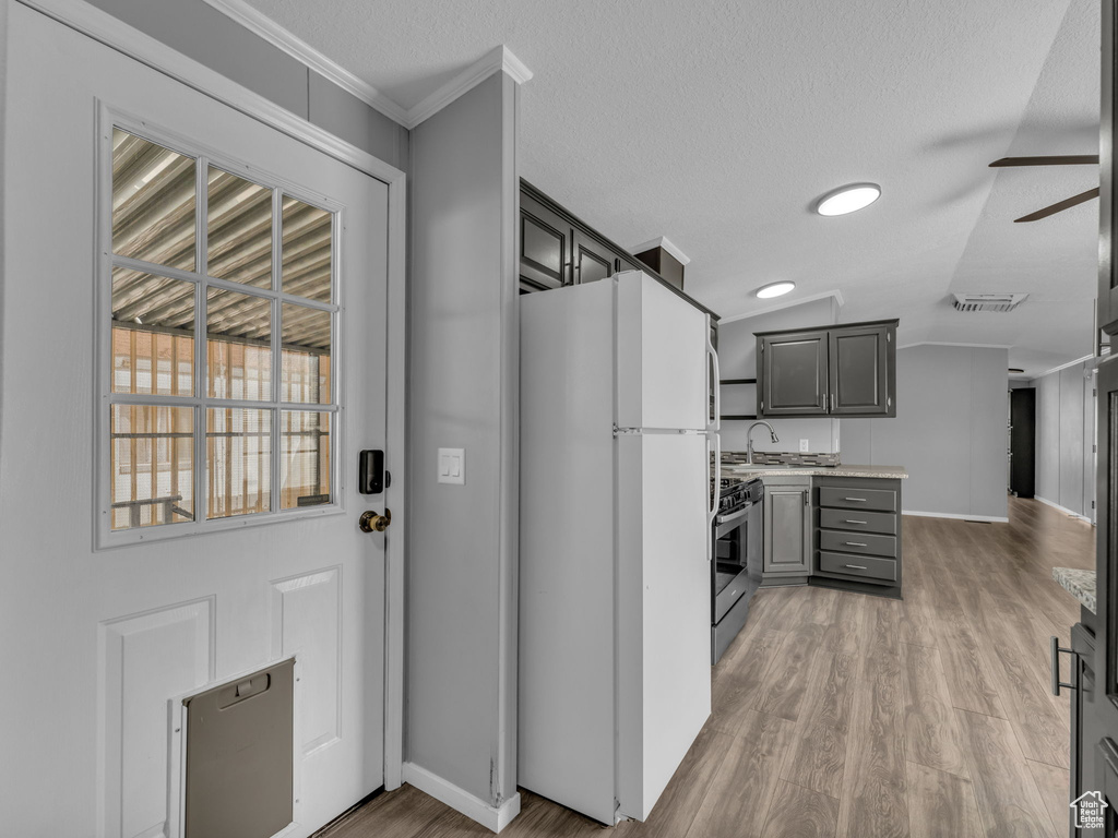 Kitchen featuring freestanding refrigerator, light countertops, light wood-type flooring, stainless steel range with gas stovetop, and a ceiling fan