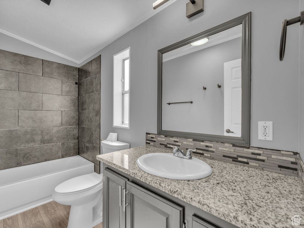 Full bathroom with vanity, backsplash, crown molding, wood finished floors, and shower / washtub combination