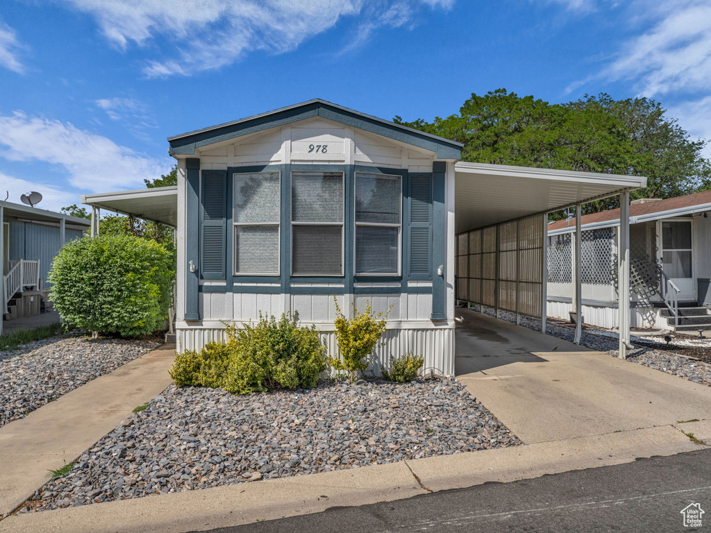 Manufactured / mobile home featuring an attached carport, concrete driveway, and entry steps
