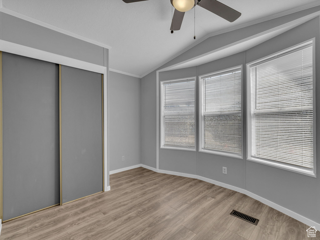 Unfurnished bedroom featuring vaulted ceiling, wood finished floors, a closet, and ceiling fan