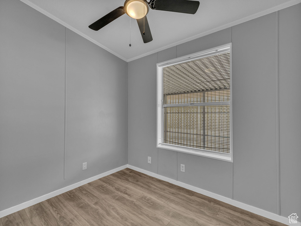 Empty room with crown molding, wood finished floors, and a ceiling fan