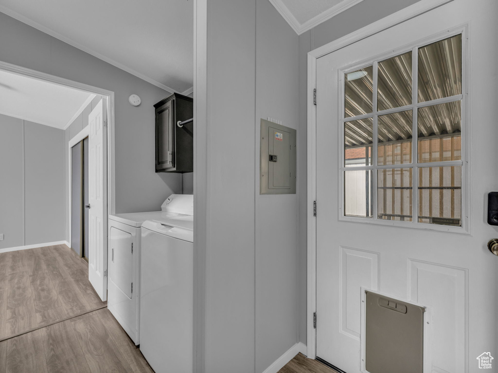 Laundry area with cabinet space, electric panel, washing machine and clothes dryer, wood finished floors, and crown molding