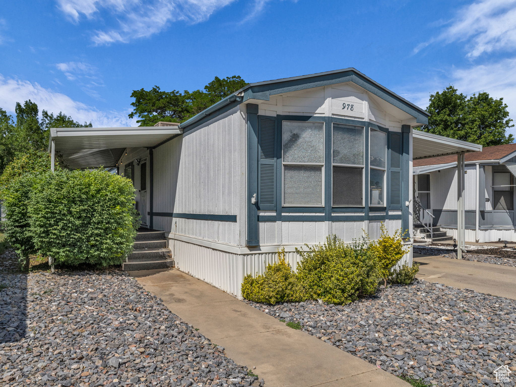 View of side of home featuring an attached carport, covered porch, and concrete driveway