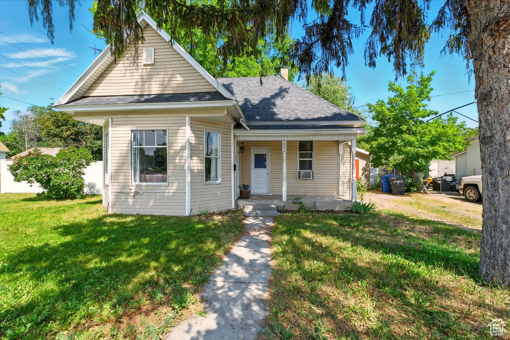 Bungalow featuring covered porch, a chimney, a front lawn, and a shingled roof