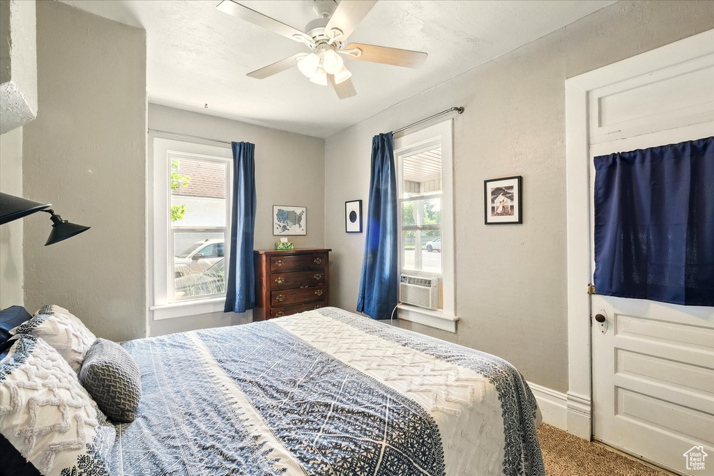 Bedroom featuring multiple windows, carpet flooring, a ceiling fan, and cooling unit