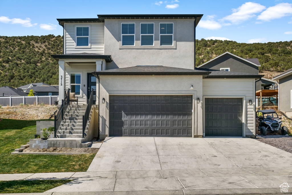 Traditional-style house featuring driveway, an attached garage, and stucco siding