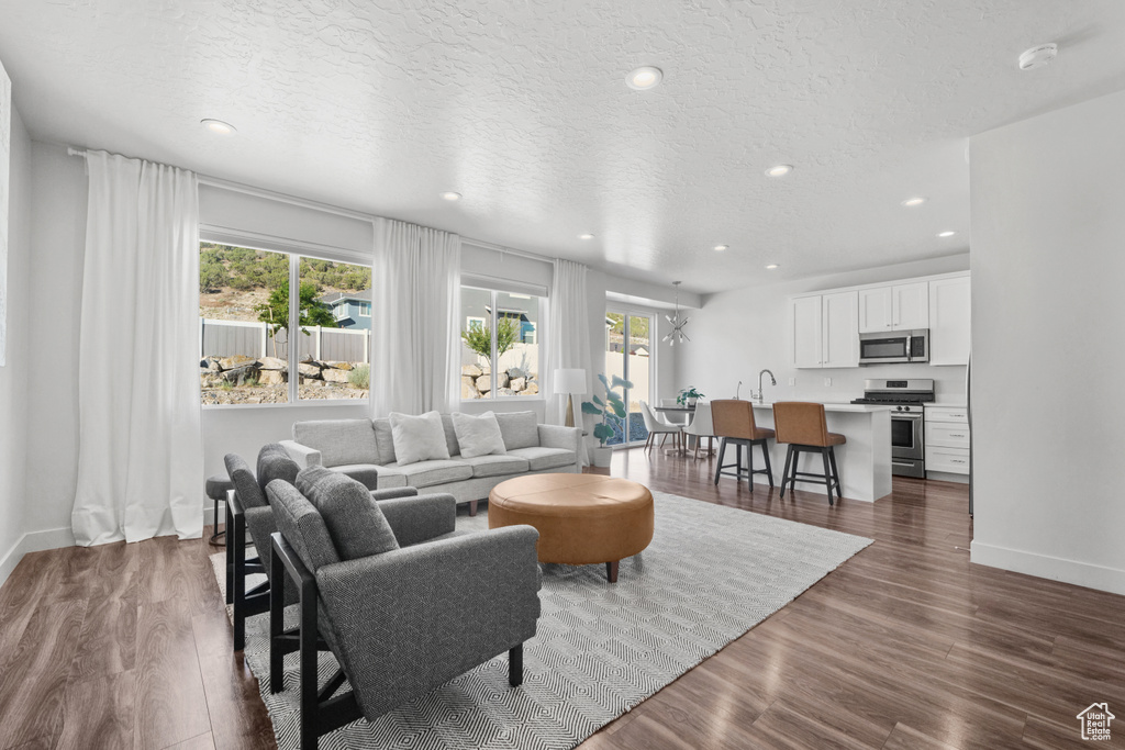 Living area featuring healthy amount of natural light, dark wood-style flooring, recessed lighting, and a textured ceiling
