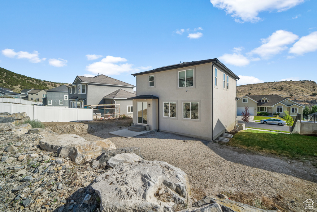 Rear view of house featuring entry steps, a residential view, a mountain view, and stucco siding