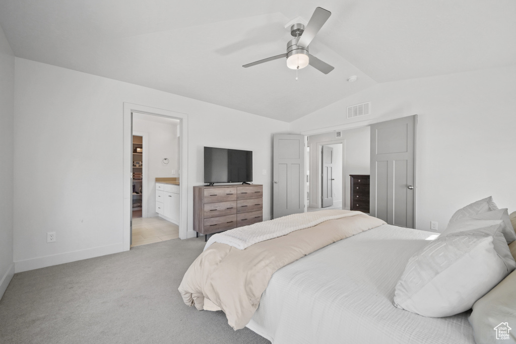 Bedroom featuring lofted ceiling, light carpet, ensuite bathroom, and a ceiling fan