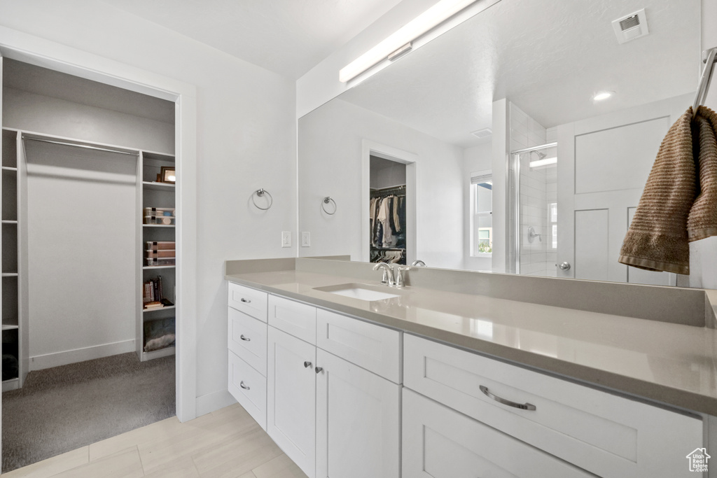 Full bathroom featuring a walk in closet, vanity, and a shower stall