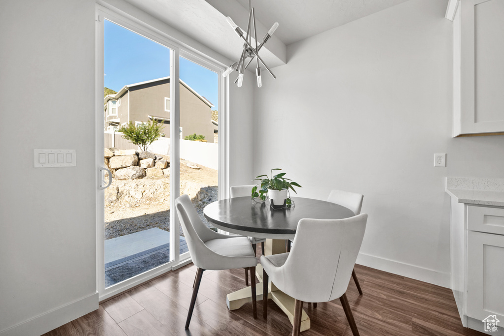 Dining area with dark wood-style floors and a chandelier