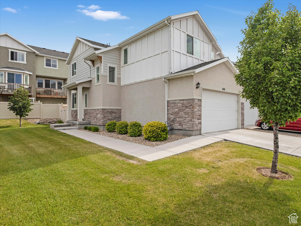 View of front of home featuring board and batten siding, stone siding, concrete driveway, and stucco siding