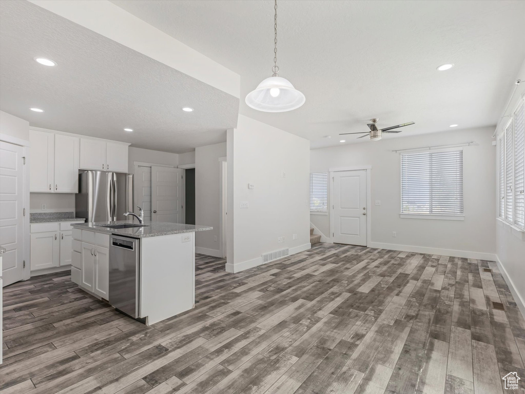 Kitchen featuring stainless steel appliances, dark wood-style flooring, open floor plan, ceiling fan, and white cabinetry
