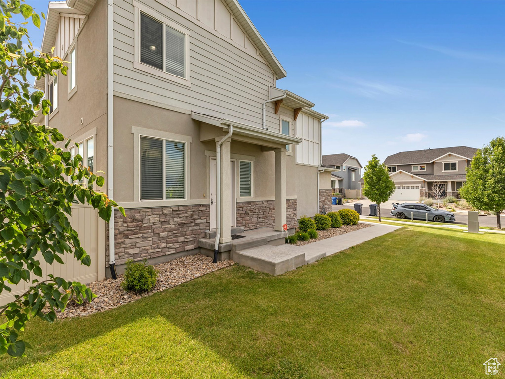 View of side of home with stone siding, a lawn, stucco siding, and a residential view