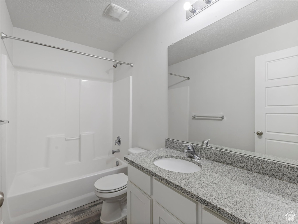Bathroom with vanity, shower / washtub combination, wood finished floors, and a textured ceiling