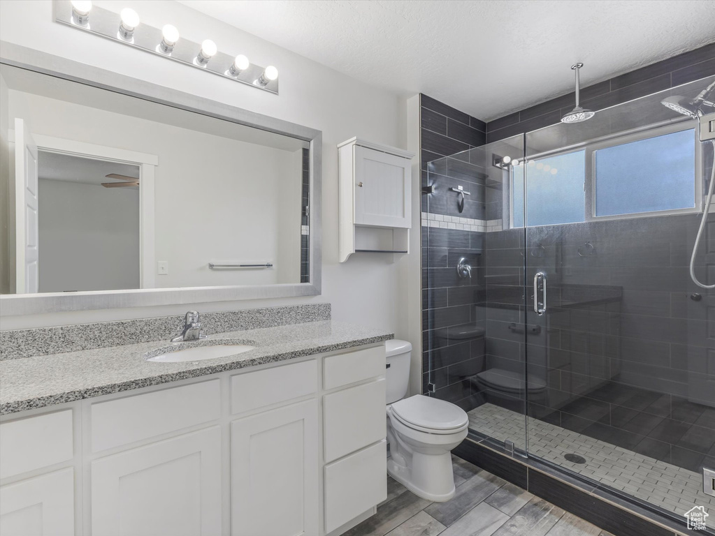 Full bath featuring vanity, a shower stall, and wood finished floors