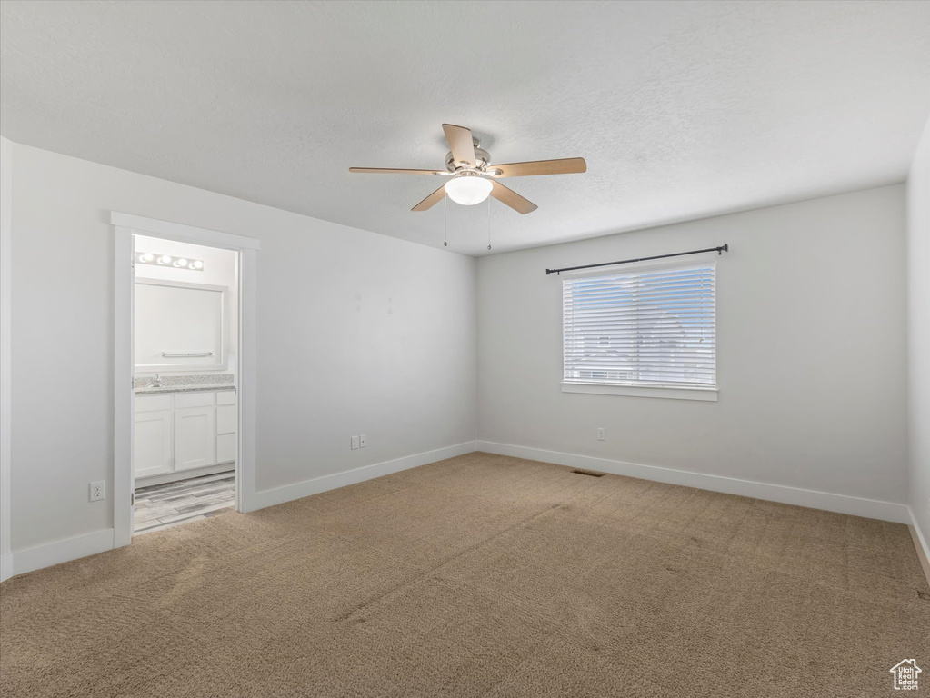 Empty room featuring ceiling fan and light carpet