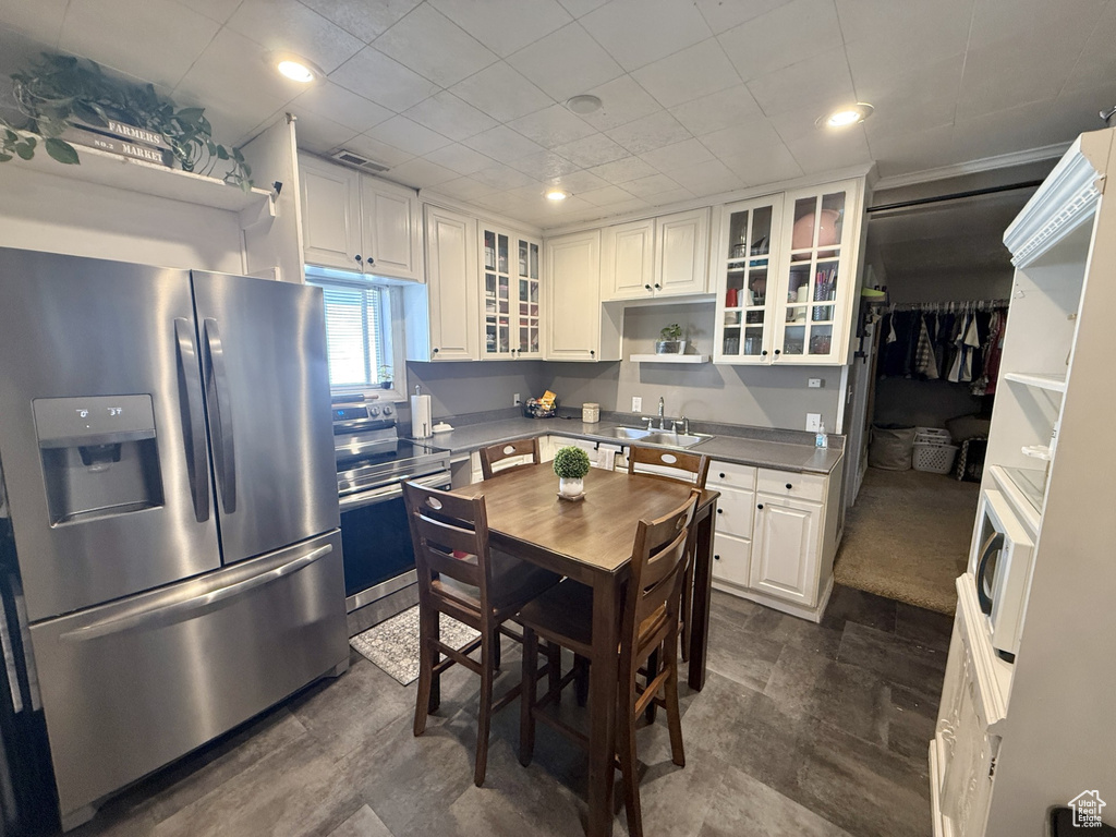 Kitchen featuring stainless steel appliances, open shelves, white cabinets, glass insert cabinets, and recessed lighting