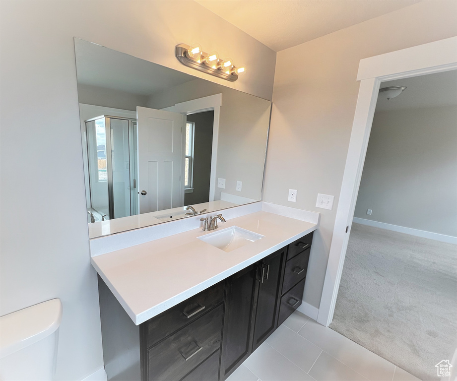 Bathroom featuring vanity, a shower with shower door, and tile patterned flooring