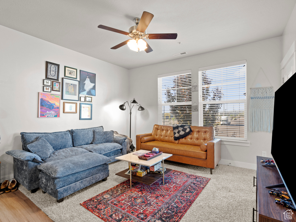 Living area with ceiling fan and baseboards