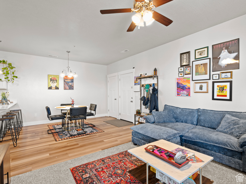 Living area with a chandelier, ceiling fan, and wood finished floors