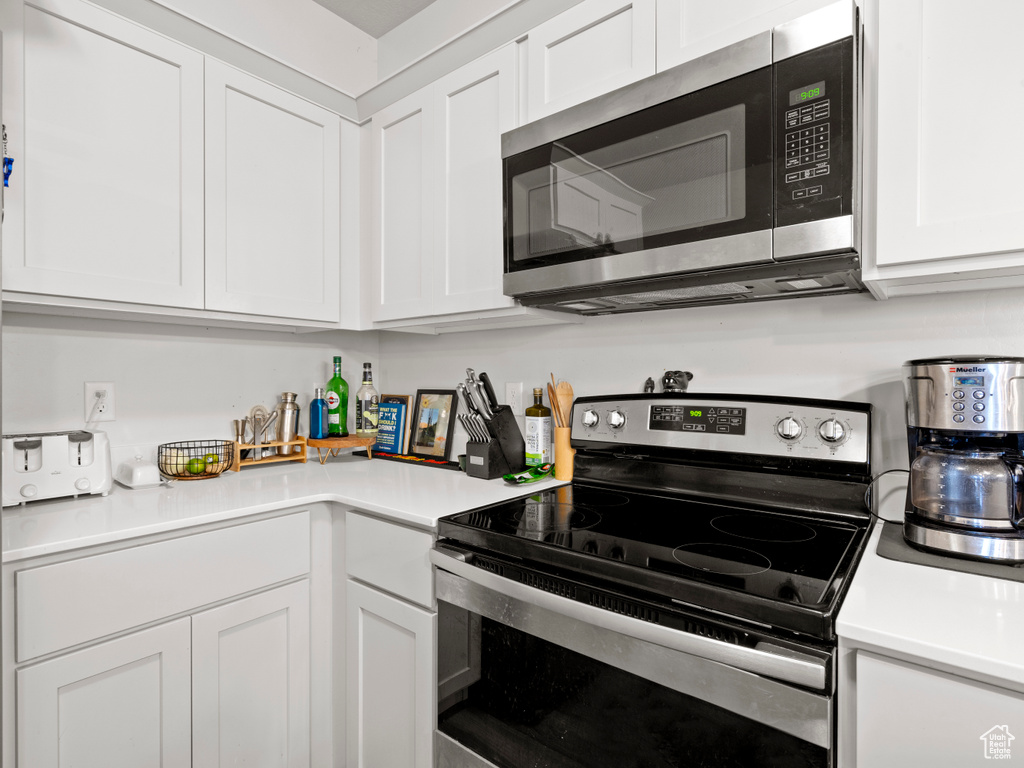 Kitchen with appliances with stainless steel finishes, white cabinets, and light countertops