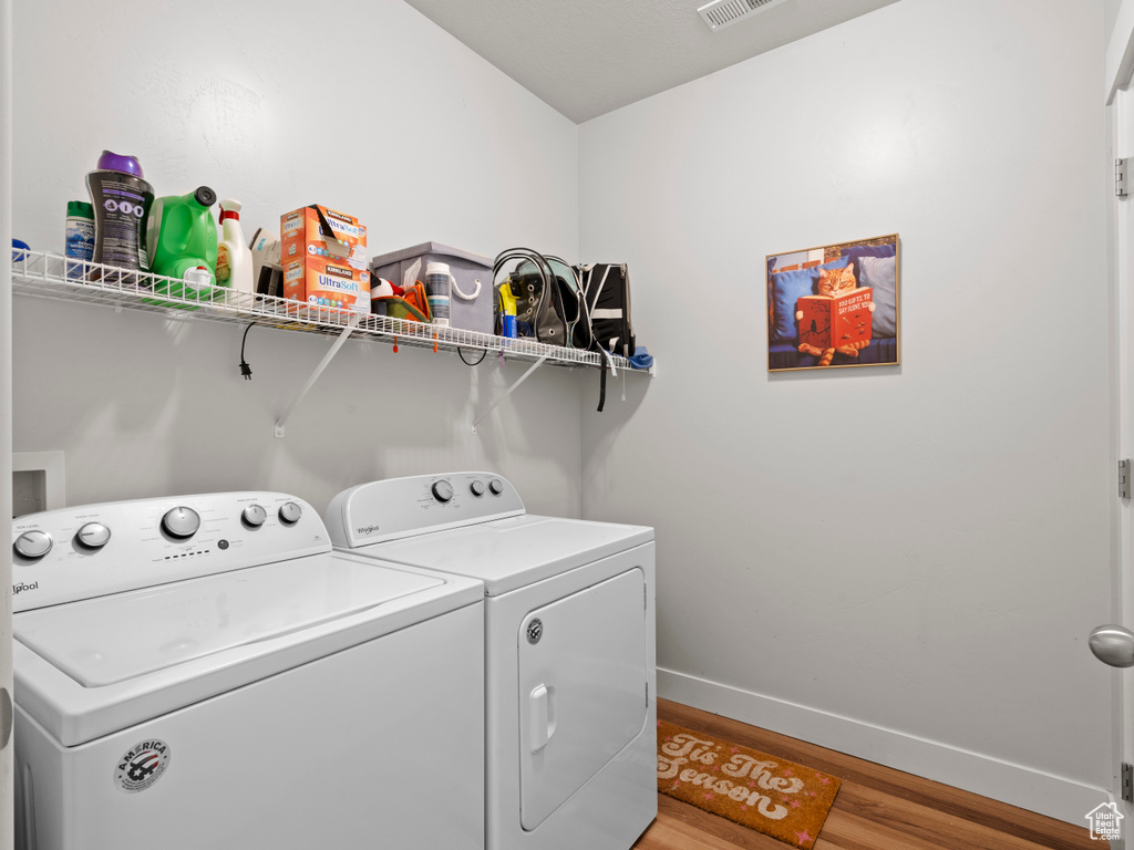 Washroom with light wood-style flooring and washer and clothes dryer