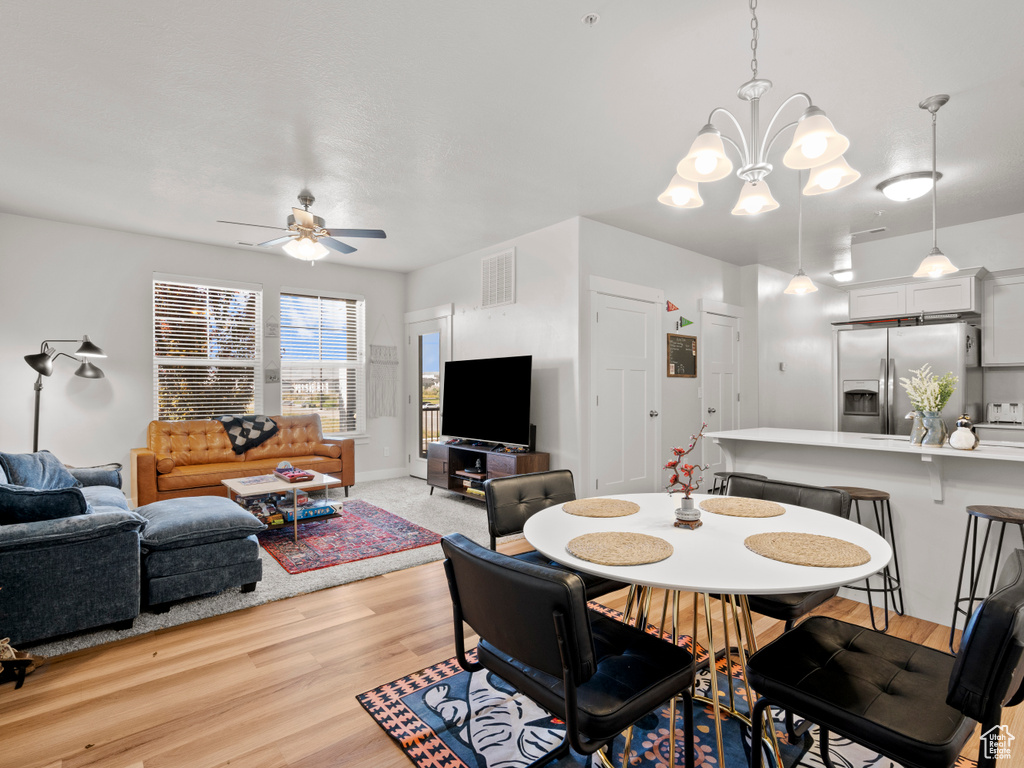 Dining room featuring ceiling fan, light wood finished floors, and a chandelier