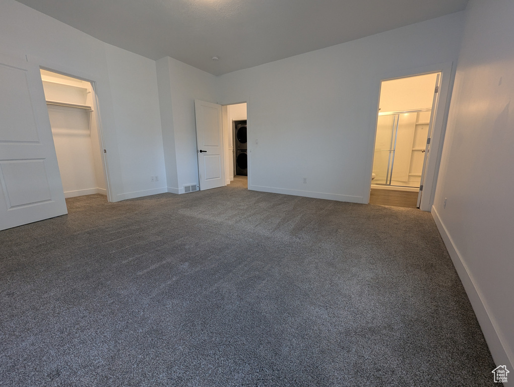 Unfurnished bedroom with carpet floors, baseboards, a spacious closet, and ensuite bath