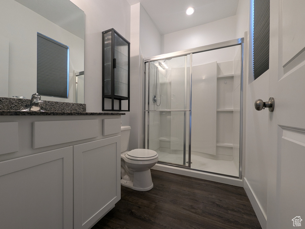 Bathroom with toilet, a stall shower, vanity, wood finished floors, and recessed lighting