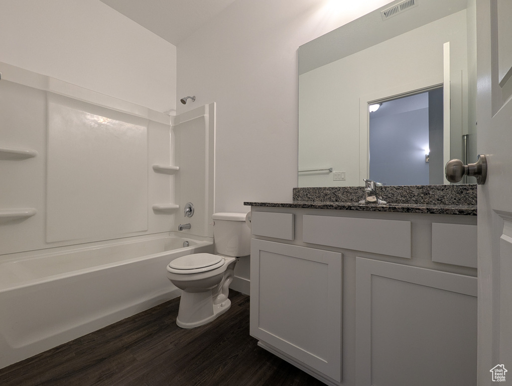 Bathroom featuring toilet, wood finished floors, vanity, and bathtub / shower combination