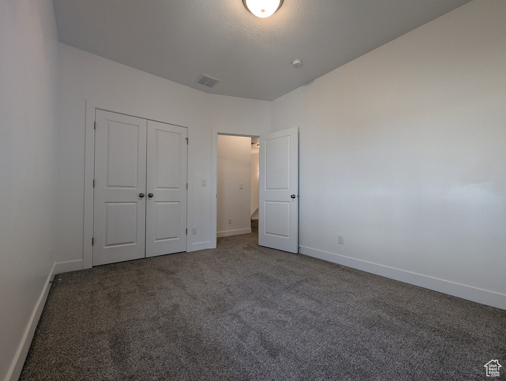 Unfurnished bedroom featuring carpet flooring, baseboards, and a closet