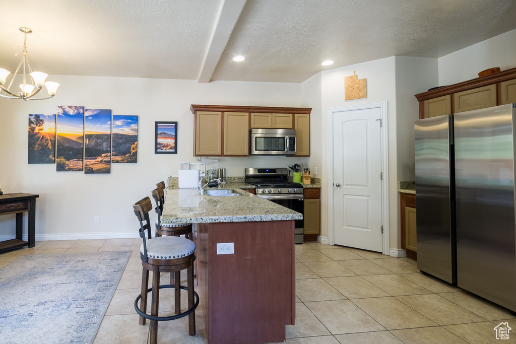 Kitchen with stainless steel appliances, a textured ceiling, a peninsula, a kitchen bar, and light tile patterned floors