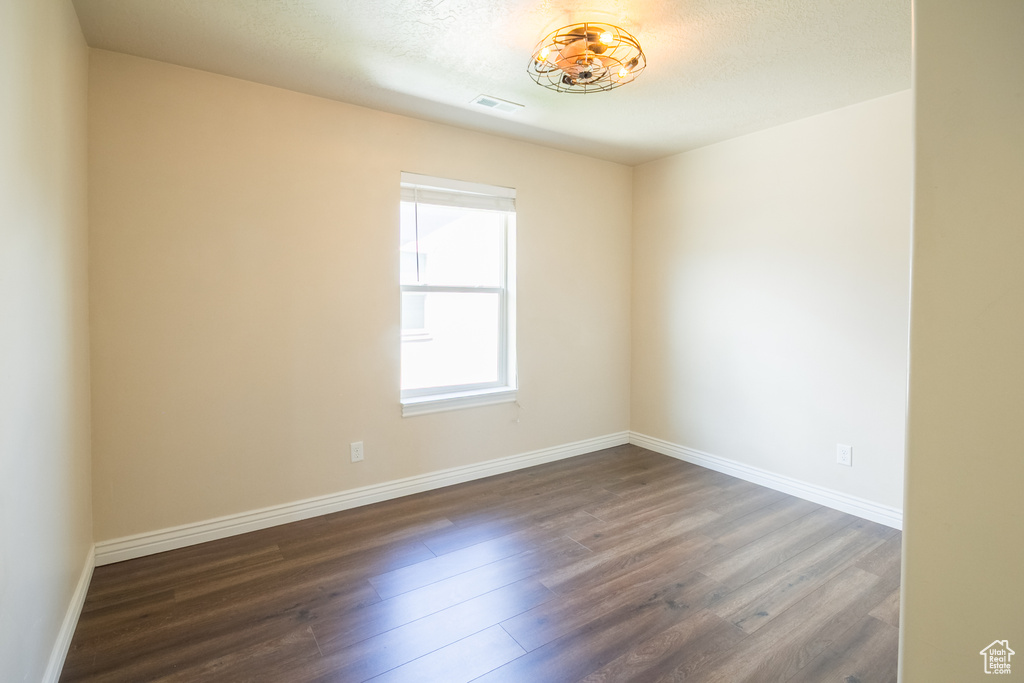 Empty room with dark wood-type flooring and baseboards